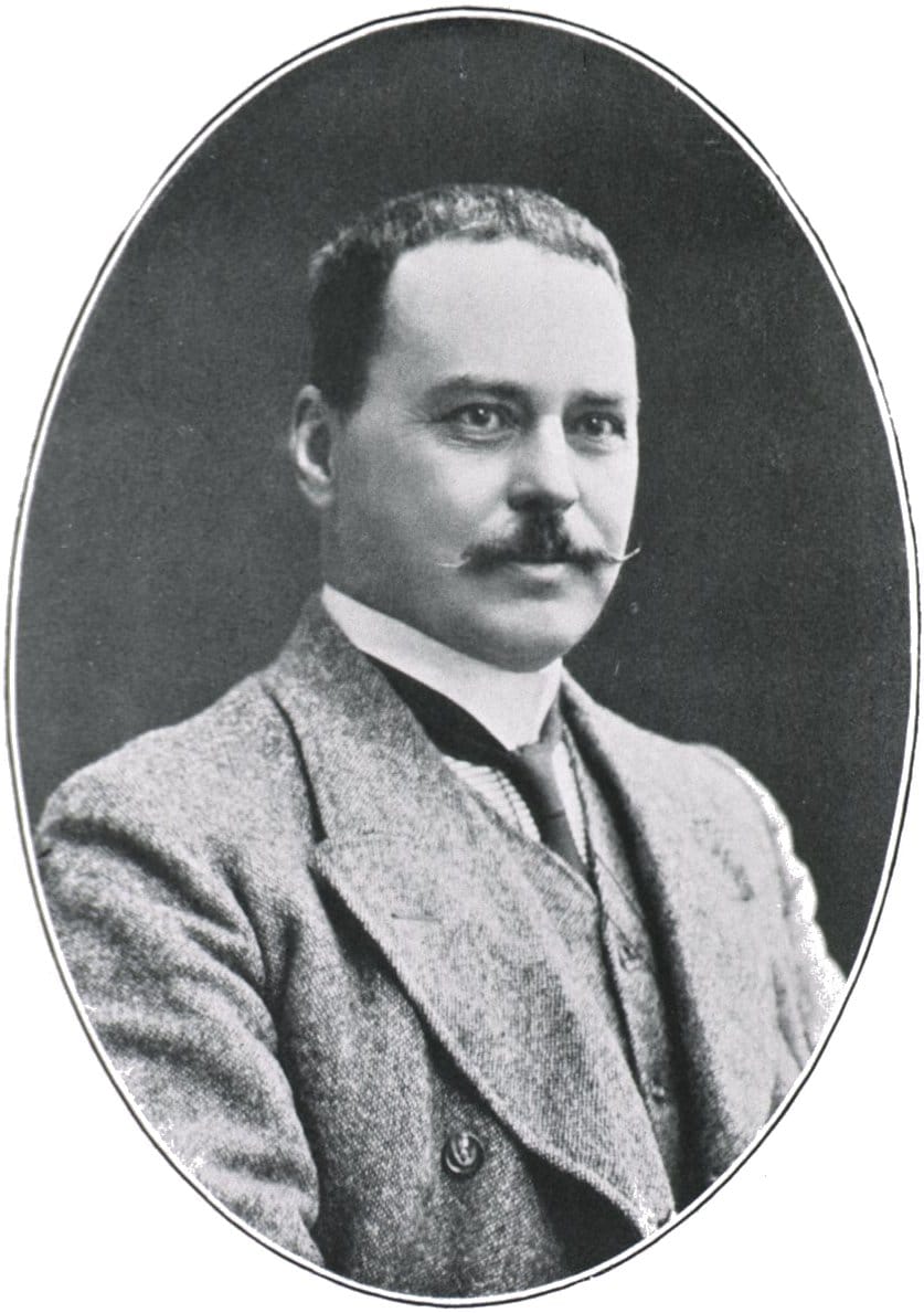 Old oval black-and-white portrait of a man with a moustache in a tweed suit and tie