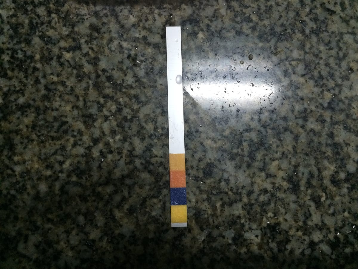 The same kind of test strip on a granite top; one of its pads has turned dark blue