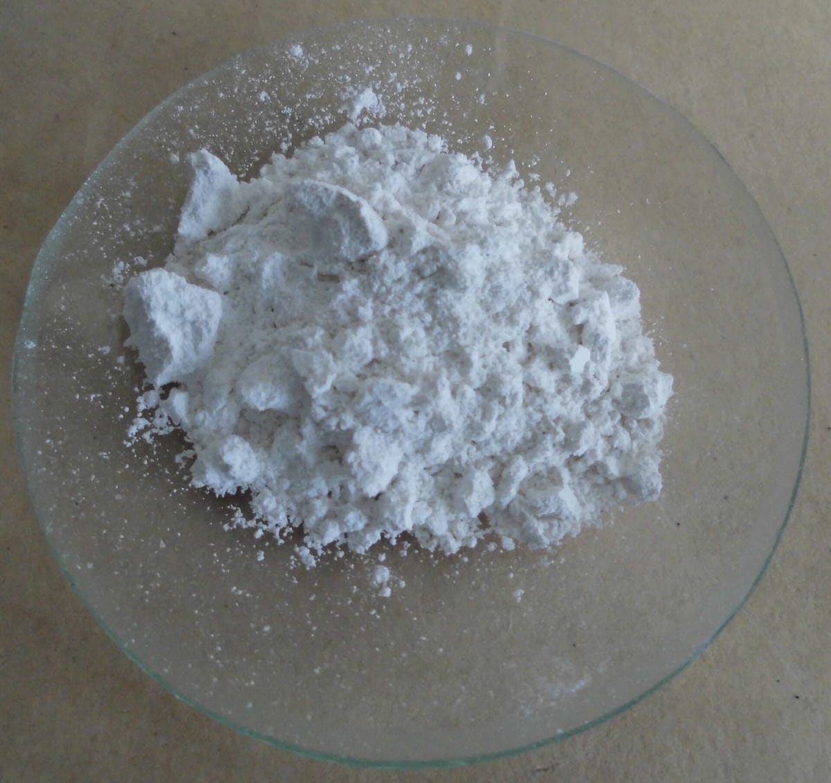 A heap of white powder and small lumps of calcium oxide on a glass dish