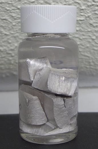 A small capped glass bottle holding silvery chunks of sodium metal covered by a clear oily liquid