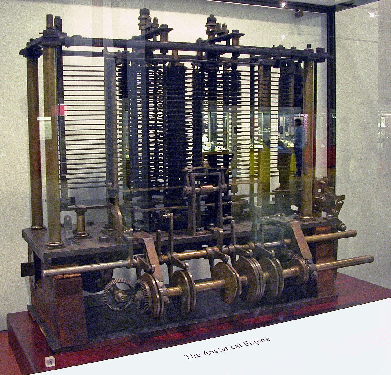 A tall machine of brass gears and columns in a glass case