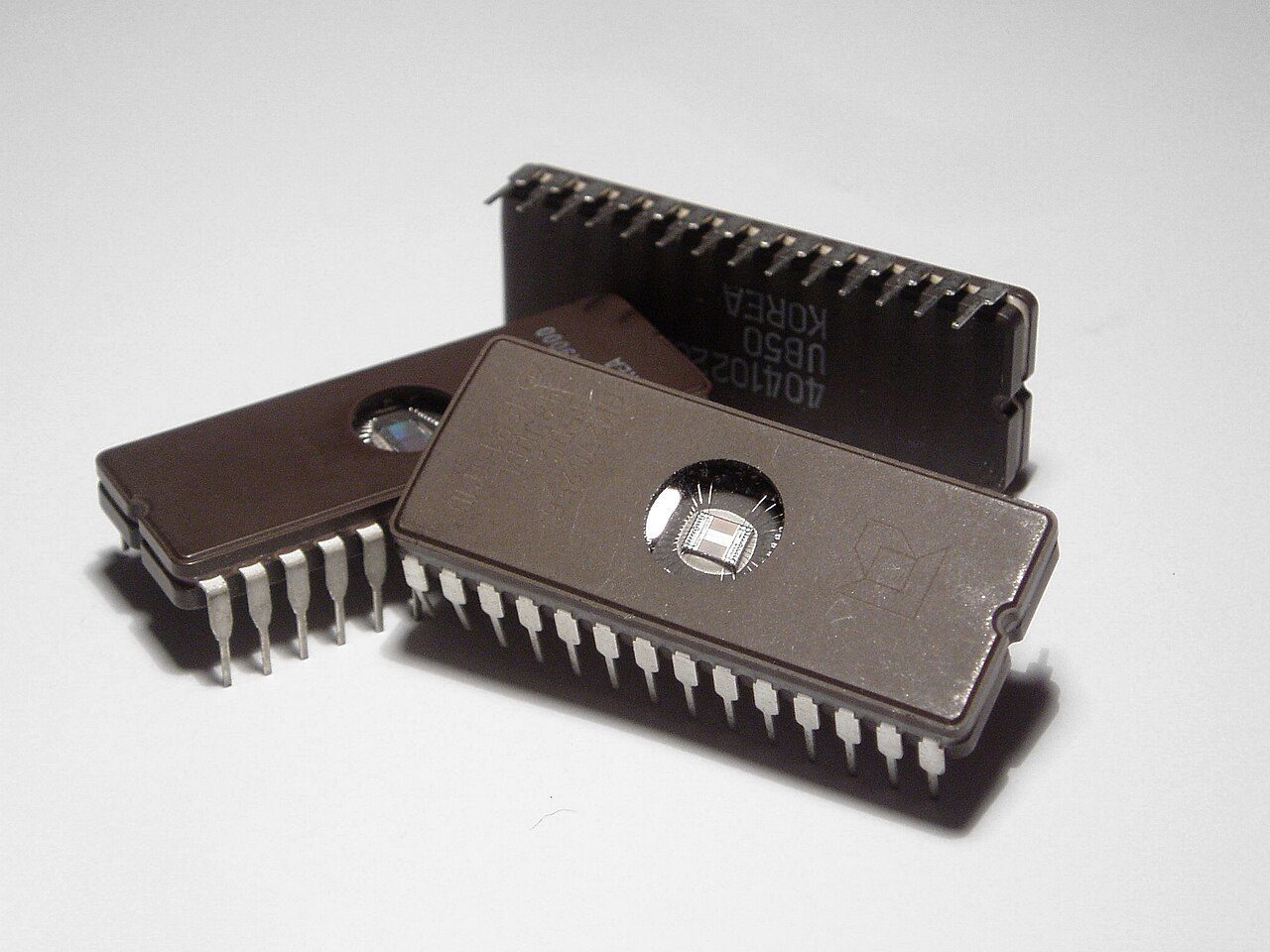Two black microchips with many metal legs; a small window shows the circuit inside