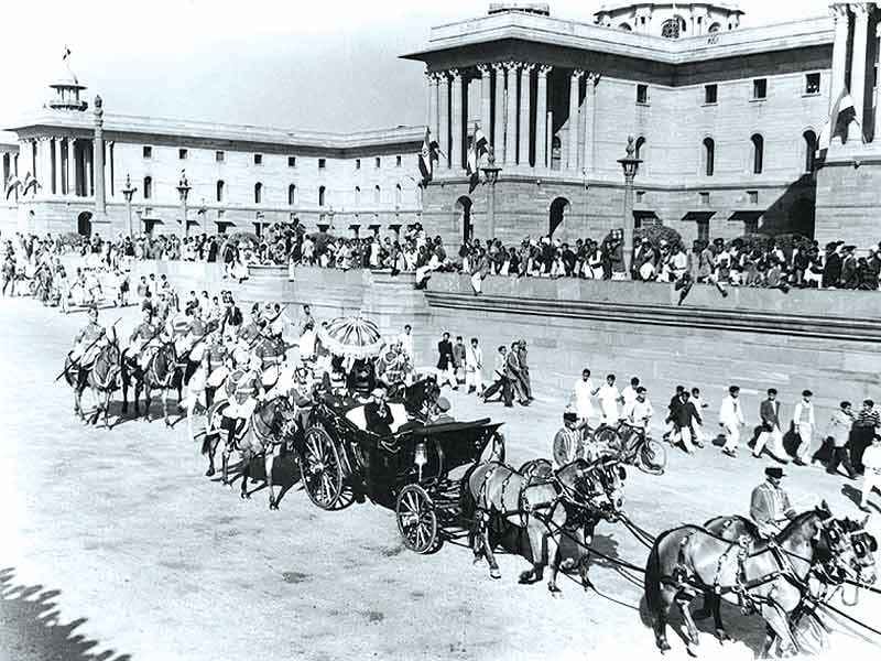 ਨਵੀਂ ਦਿੱਲੀ ਦੀ ਚੌੜੀ ਸੜਕ ਉੱਤੇ ਘੋੜਿਆਂ ਵਾਲੀ ਸ਼ਾਹੀ ਬੱਘੀ, ਨਾਲ ਭੀੜ ਅਤੇ ਸਿਪਾਹੀ