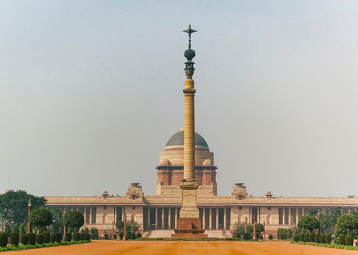 The long sandstone front of Rashtrapati Bhavan with its central dome, and a tall column in the forecourt
