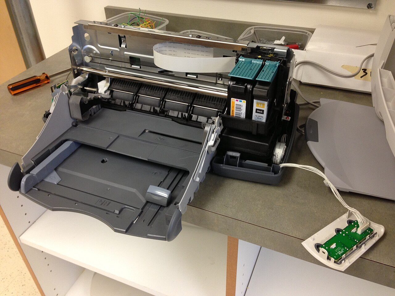 An inkjet printer with its plastic covers removed, showing the ink cartridge carriage and rollers