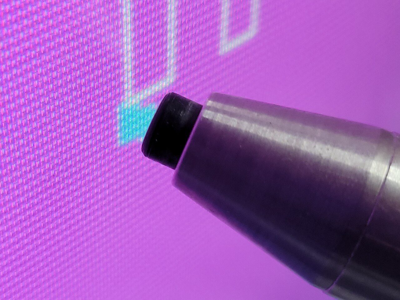 A metal pen-shaped device pressed against the glass of an old CRT monitor