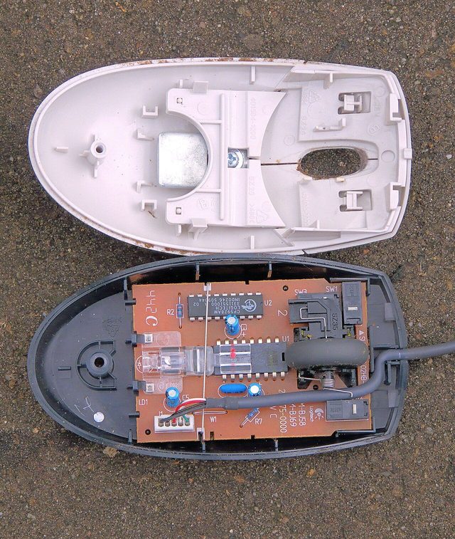 An optical mouse opened into two halves, showing the circuit board, the scroll wheel and a small light