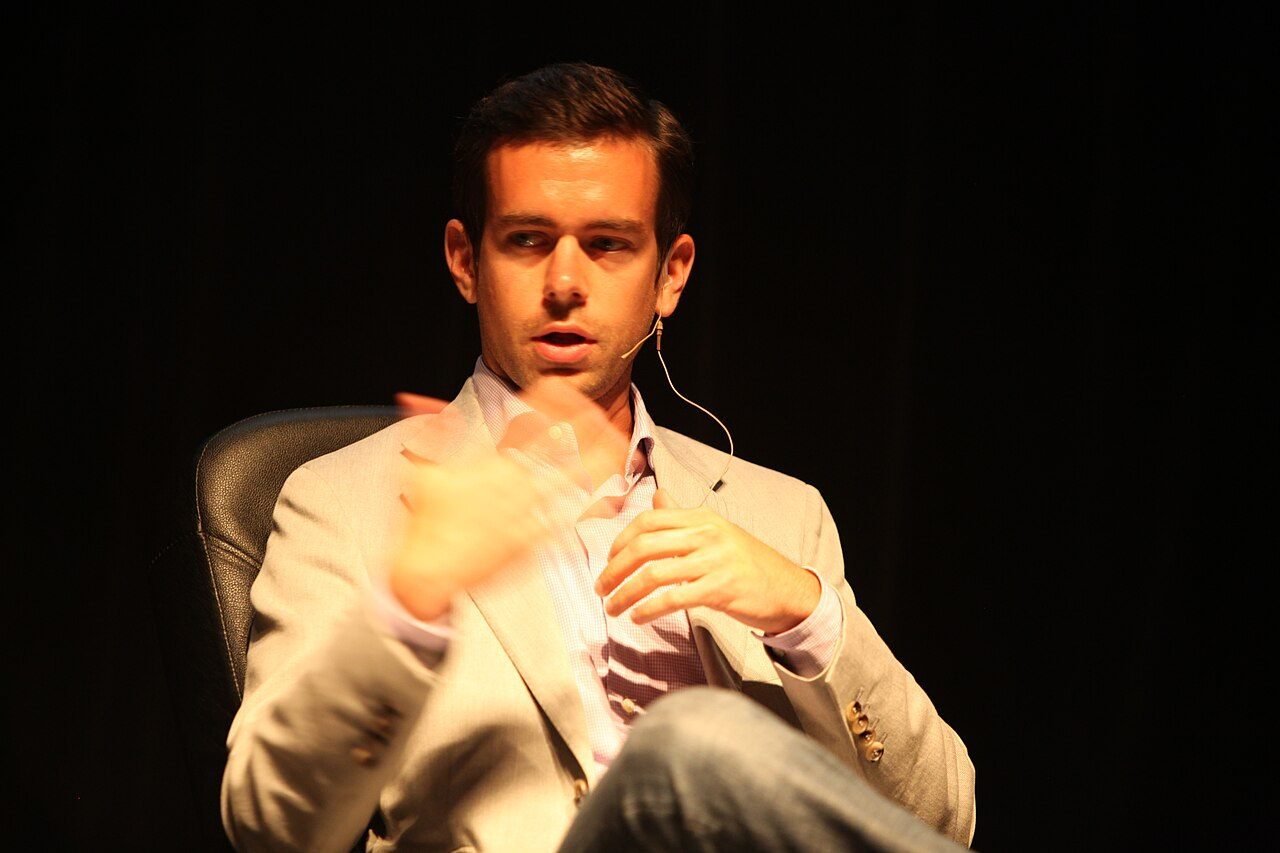 Jack Dorsey in a light jacket, seated and speaking on stage at a tech event in 2009