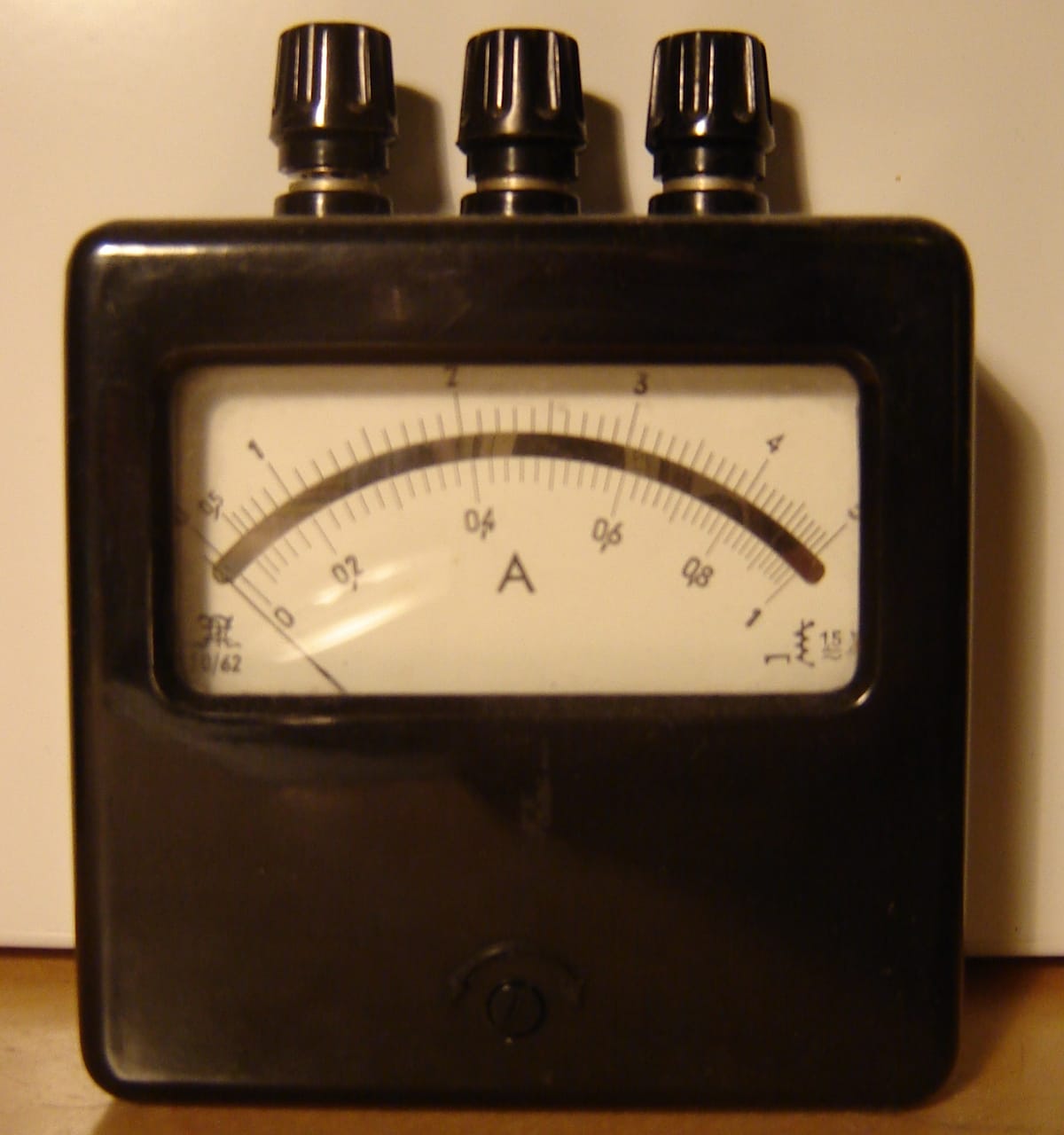 An old black meter with three terminal knobs on top and a dial marked A, with scales up to 1 and 5