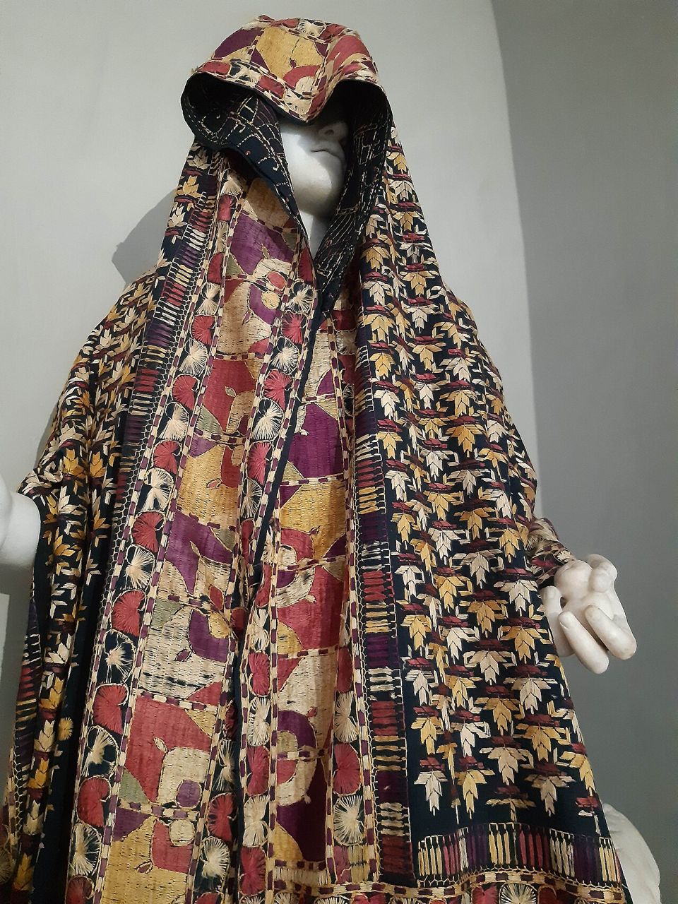 A bagh shawl draped on a mannequin, its whole surface covered with dense silk embroidery