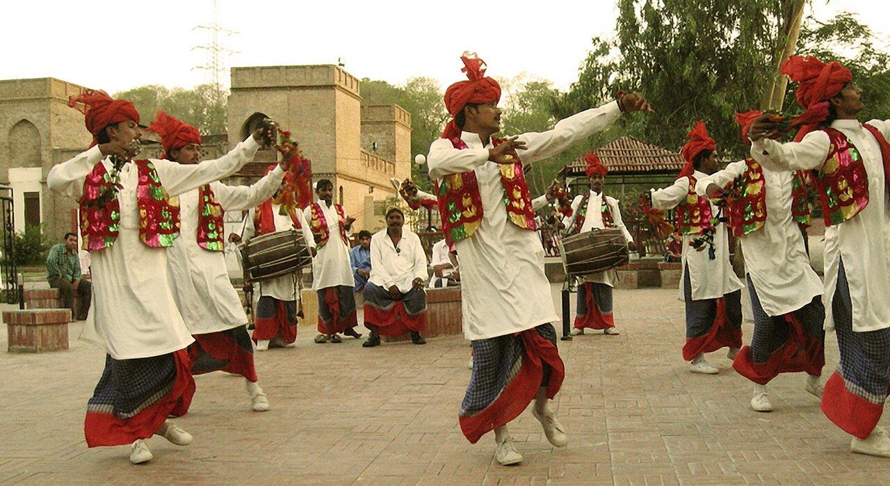 Bhangra dancers in white kurtas, checked chadras and red turbans