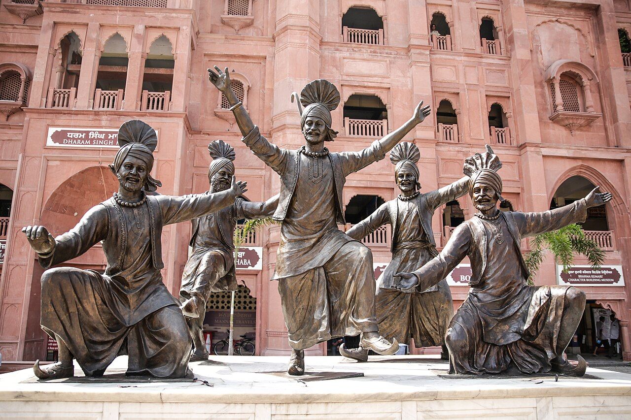 ਅੰਮ੍ਰਿਤਸਰ ਵਿੱਚ ਬਾਹਾਂ ਉੱਚੀਆਂ ਕਰਕੇ ਭੰਗੜਾ ਪਾਉਂਦੇ ਗੱਭਰੂਆਂ ਦੇ ਕਾਂਸੀ ਦੇ ਬੁੱਤ — ਤੁਰਲੇ ਵਾਲੀ ਪੱਗ, ਜੁੱਗੀ ਅਤੇ ਚਾਦਰਾ
