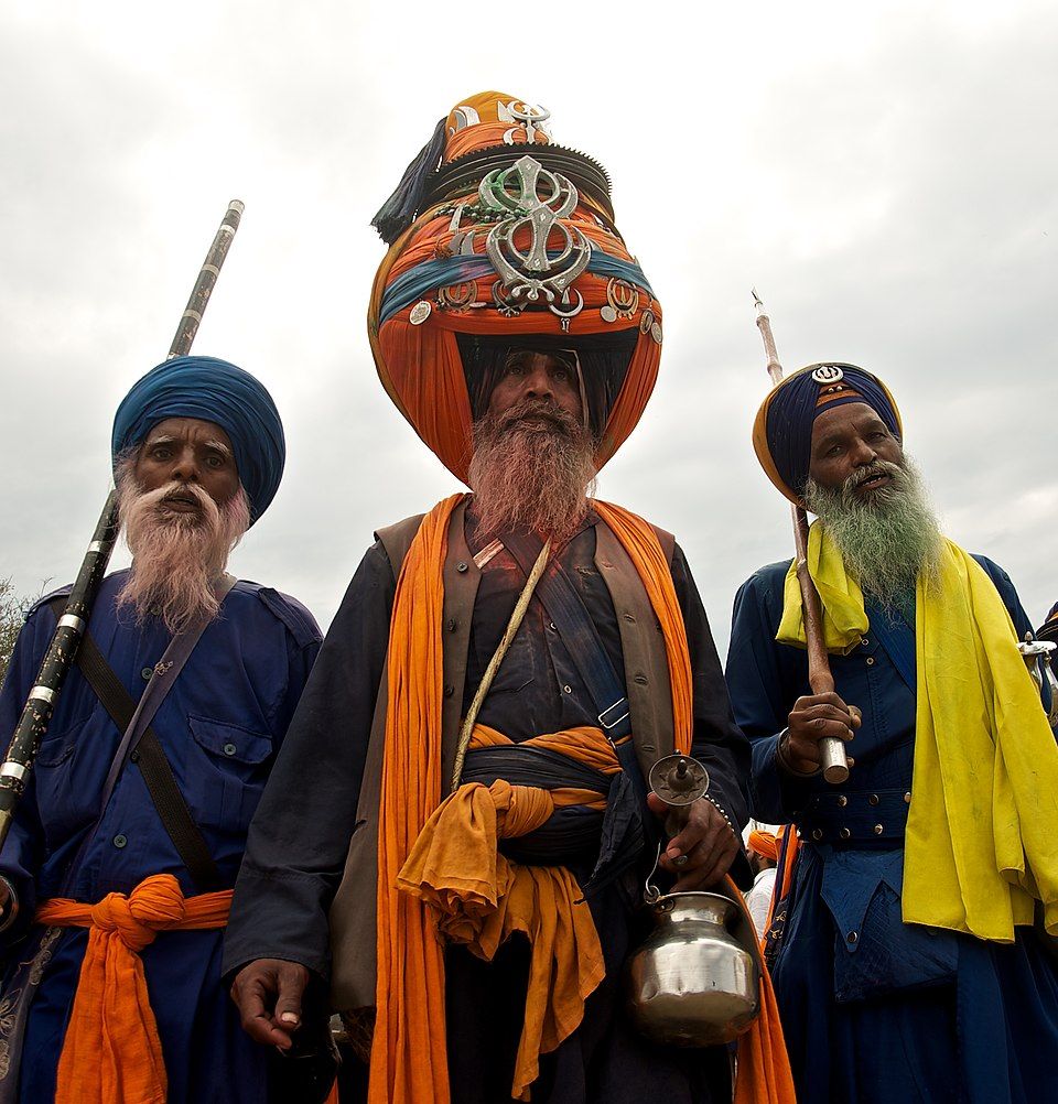 Three Nihang Sikhs in blue and saffron robes and tall turbans at Hola Mohalla, Anandpur Sahib