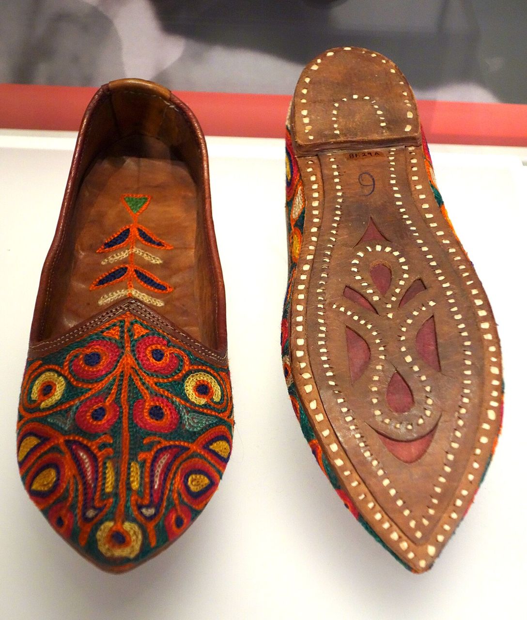 A pair of Punjabi juttis with bright embroidered uppers and a studded leather sole