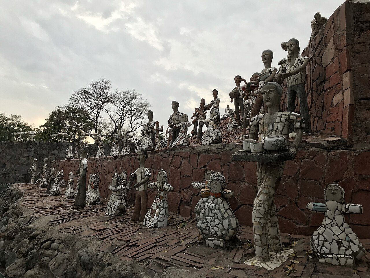 Rows of figures made from broken tiles and waste material along a stone wall in the Rock Garden, Chandigarh