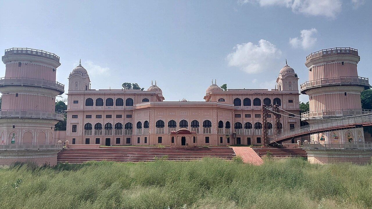 The pink Sheesh Mahal, Patiala, with two round towers and a suspension bridge across the lake