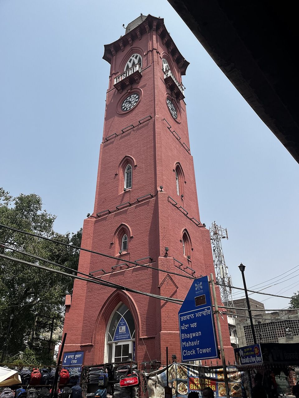 Tall red-brick clock tower in a busy Ludhiana street