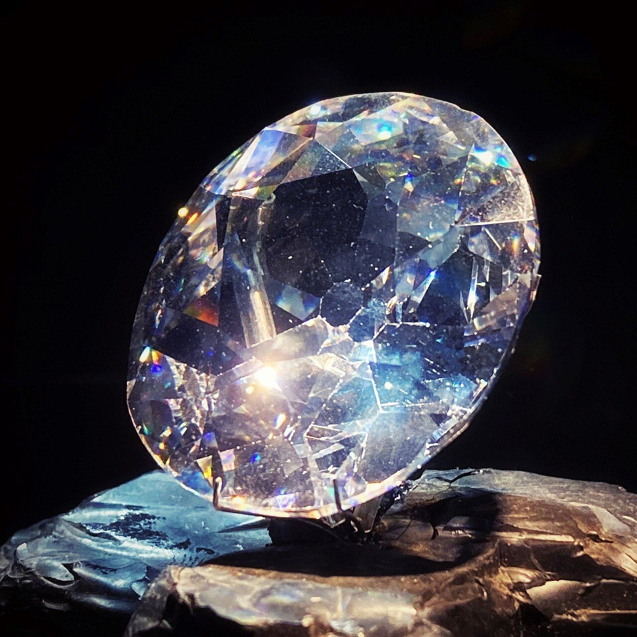 A glass replica of the Koh-i-Noor diamond lit against a dark background