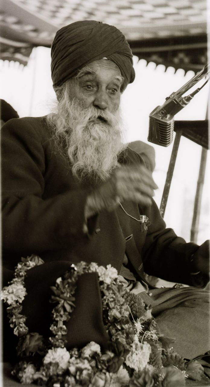 Photograph of Master Tara Singh with a long white beard, speaking at a microphone
