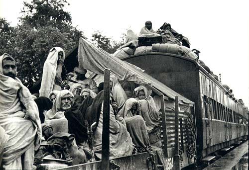 Black-and-white photo of refugees crowded on and around a train