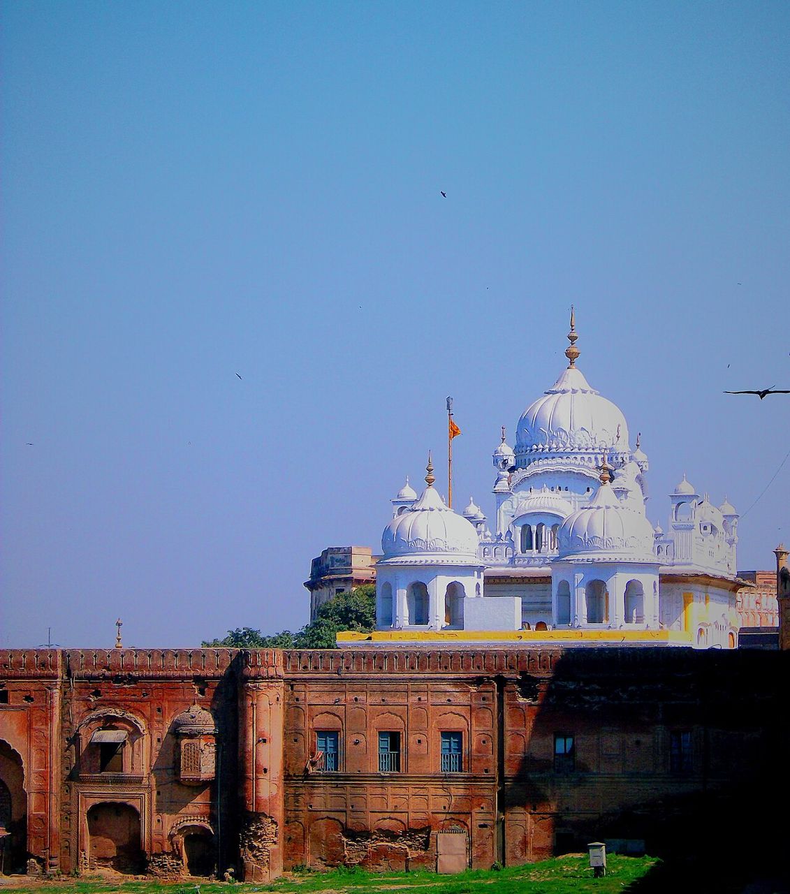 White domes of the Samadhi of Maharaja Ranjit Singh rising behind an old brick wall in Lahore