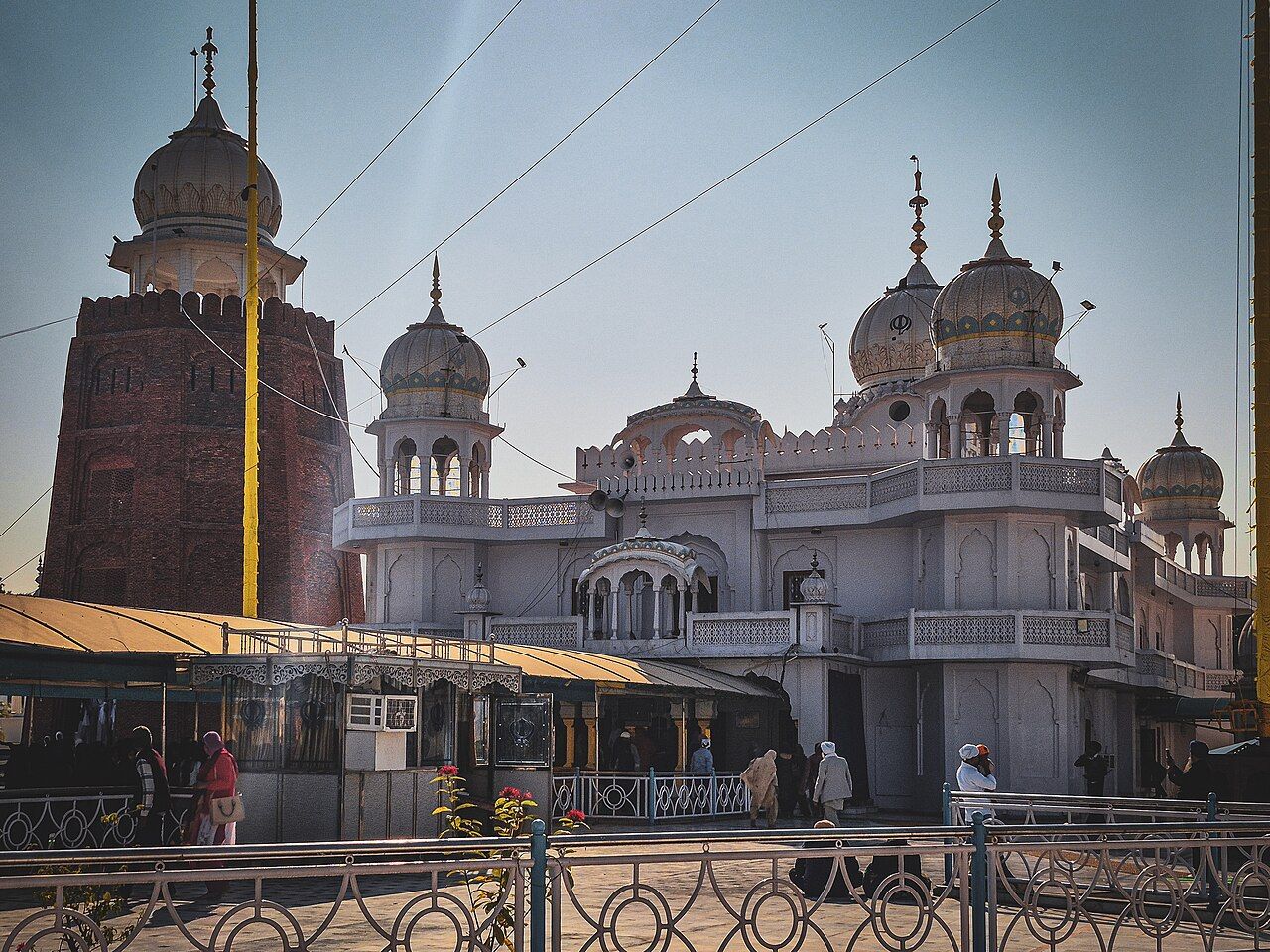 White domes of Takht Sri Damdama Sahib beside an old red-brick tower at Talwandi Sabo