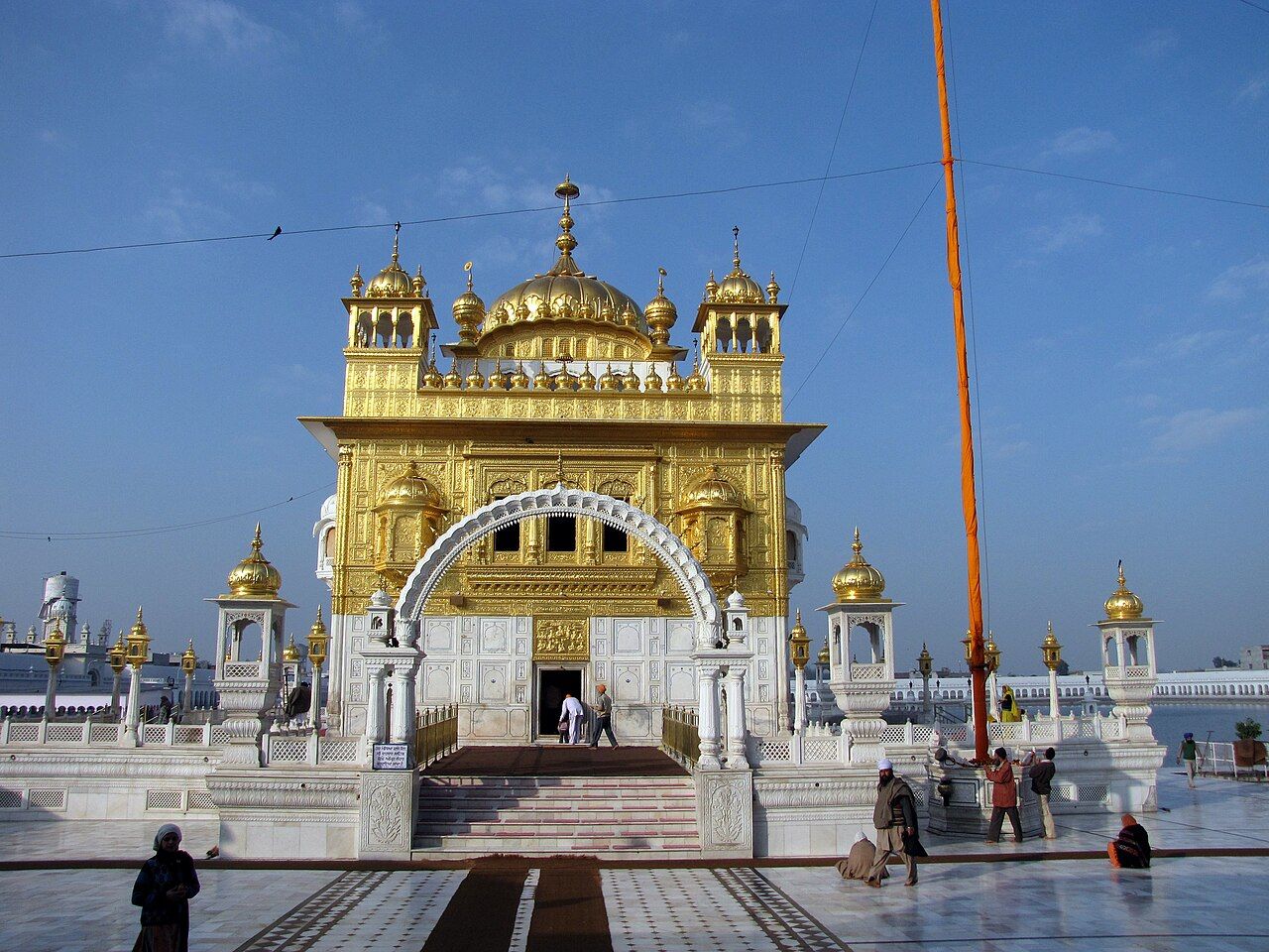 Golden gurdwara building with an arched gateway beside a marble walkway, Tarn Taran