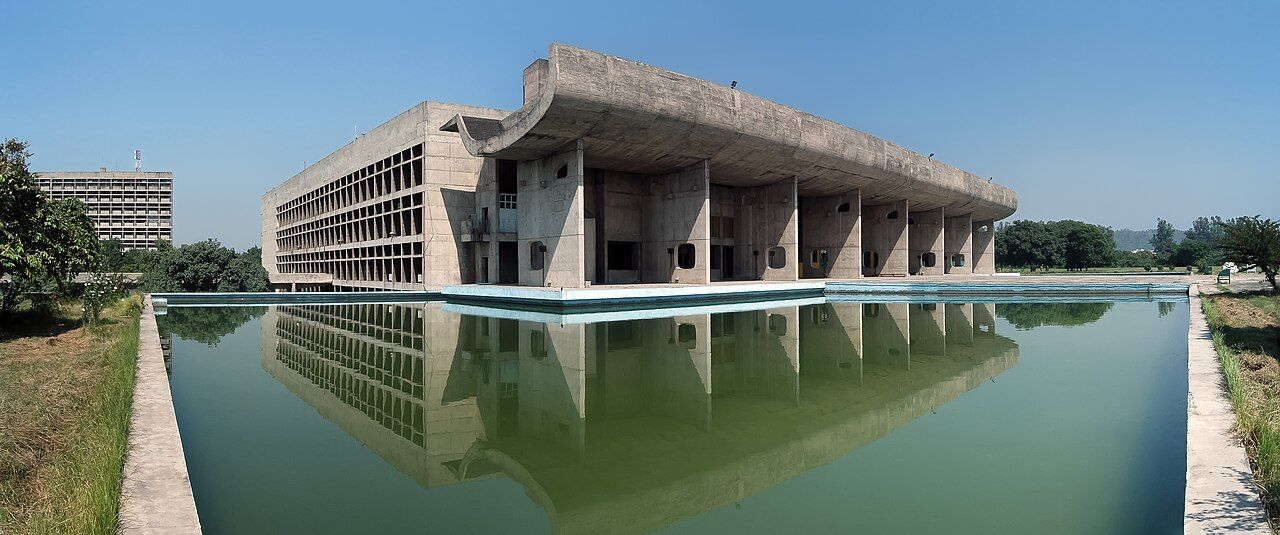 The concrete Palace of Assembly in Chandigarh reflected in a long pool